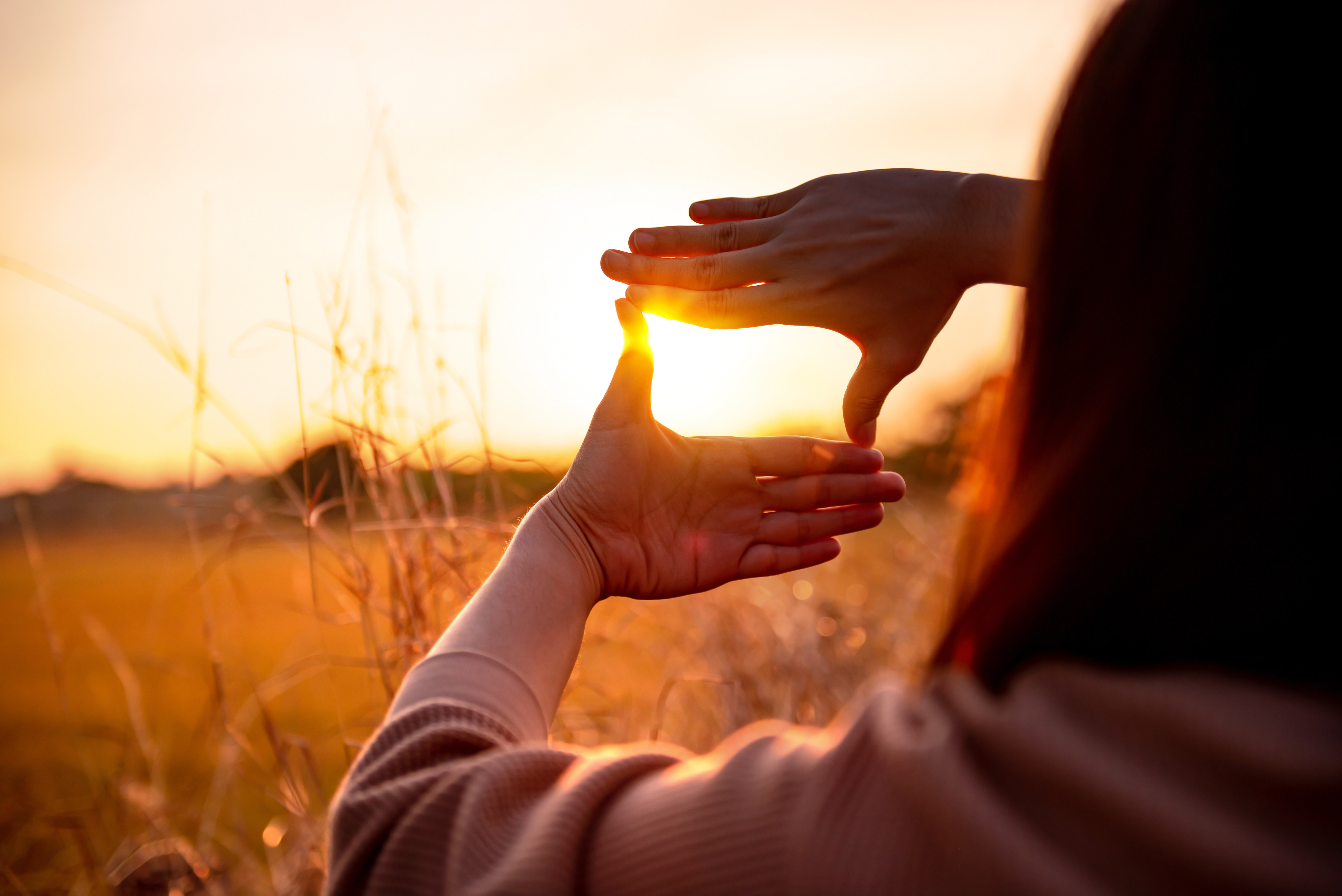 A young women framing the sun with her hands